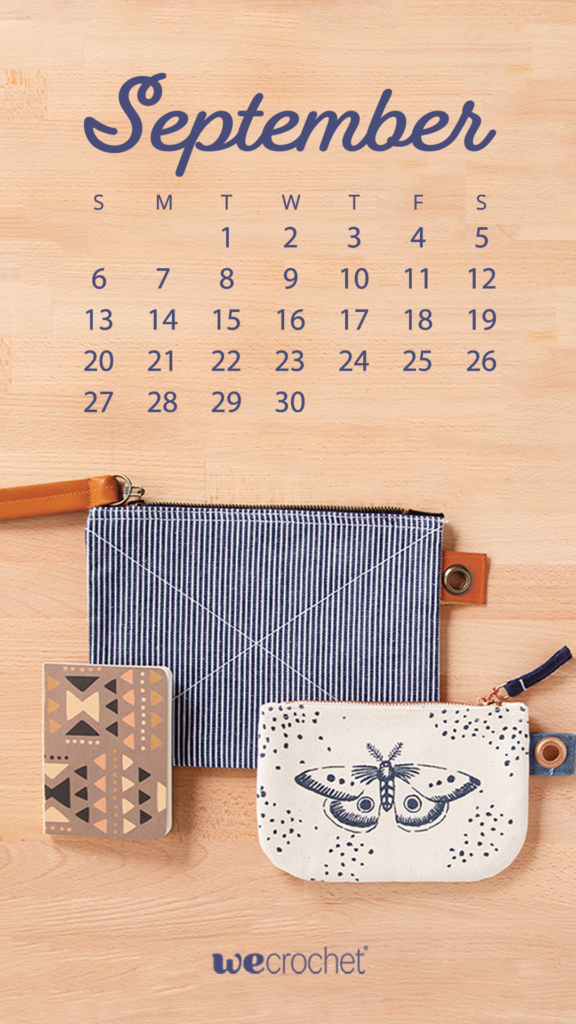 A September 2020 calendar with a light wood background and two pouches and a notebook arranged on a table