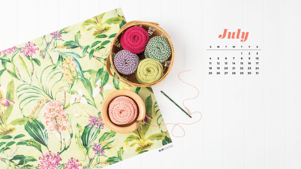 A top-down view of a white background with a floral pattern paper on it, with a yarn bowl filled with colorful cotton yarn. A July 2021 calendar in the upper corner.
