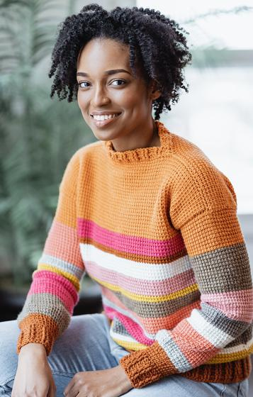 A model wears a brightly-colored striped sweater made in Tunisian crochet.