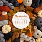 A large pile of various yarn in fall colors (rust, pumpkin, gray, maroon), along with assorted decorative pumpkins. A white circle in the middle with the Sept 2021 calendar inside it.